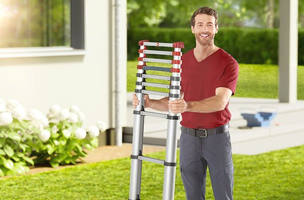 A man next to a house is holding a Hailo FlexLine telescopic ladder