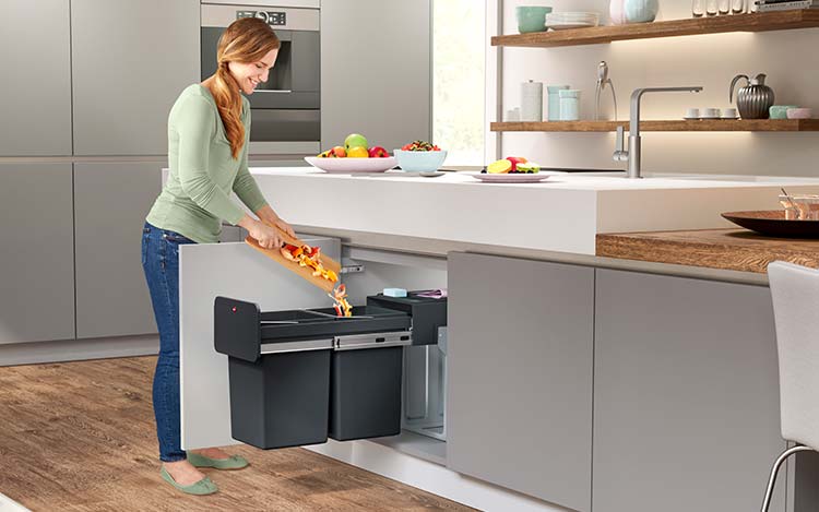 A woman disposes of fruit waste in a built-in waste bin