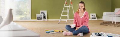 A woman is sitting on the floor of a living room, in the background is a Hailo L60 StandardLineladder