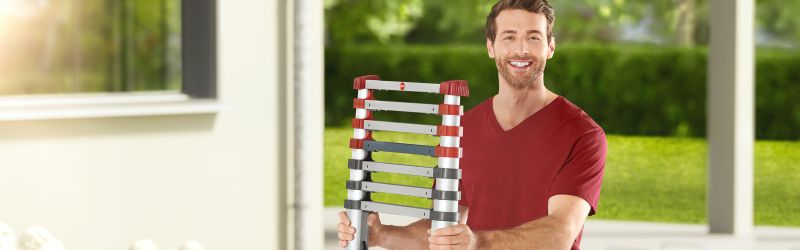 A man in the garden is holding a Hailo FlexLine rung ladder