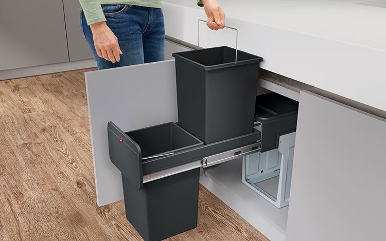 A person pulls an inner bucket out of a built-in waste bin