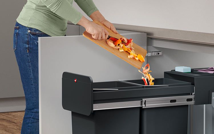 A person disposes of fruit waste in a built-in waste bin