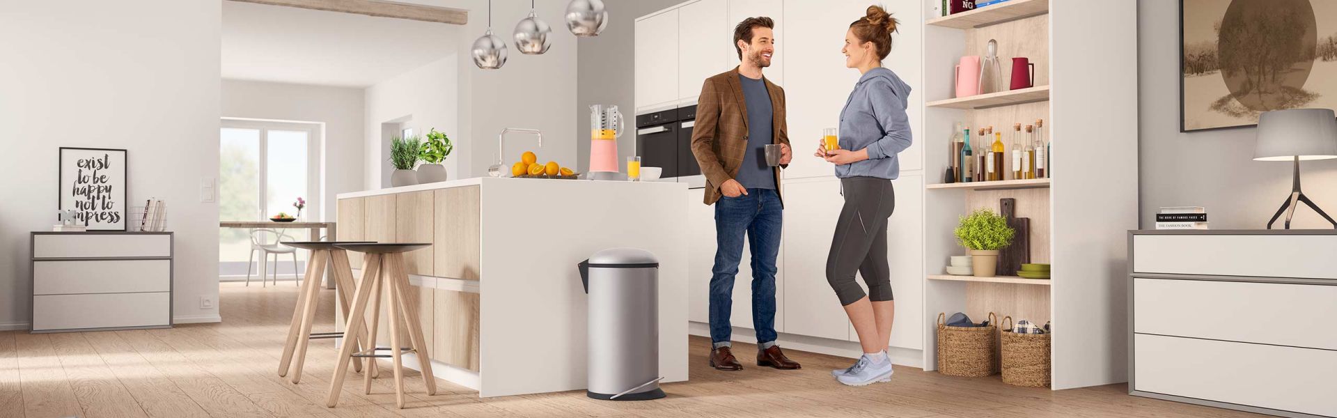 2 people standing in a kitchen, next to them a Hailo Harmony L waste bin