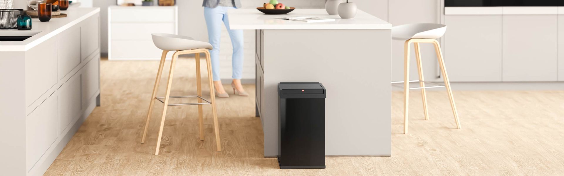 A black sqared waste bin is standing in a kitchen